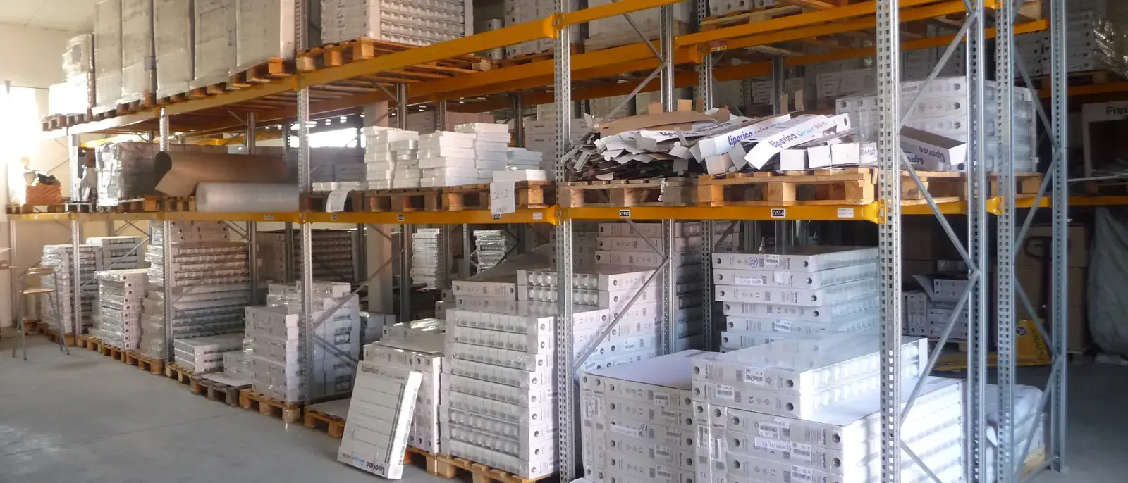 Scaffalature industriali con bancali e materiale imballato in un magazzino aziendale.