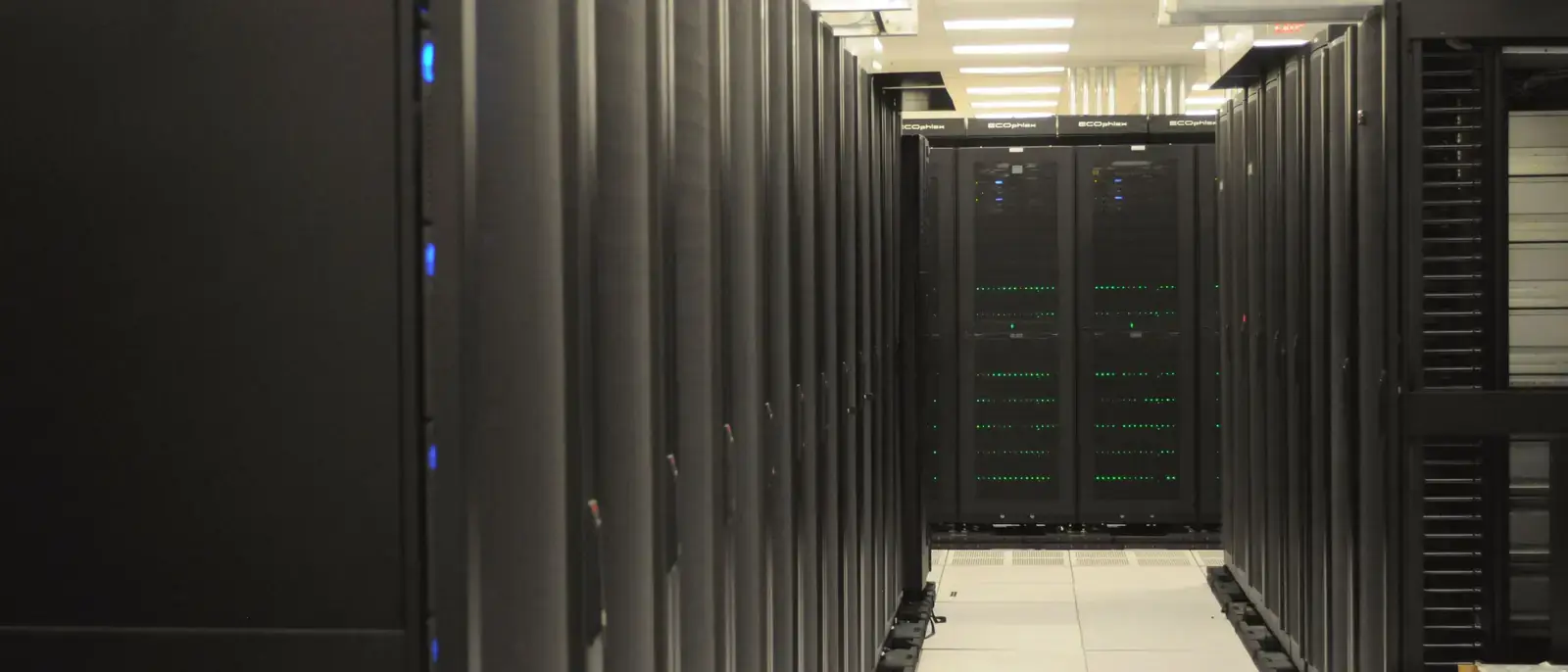 Un corridoio fra due file di armadi in una sala server, con le spie accese.